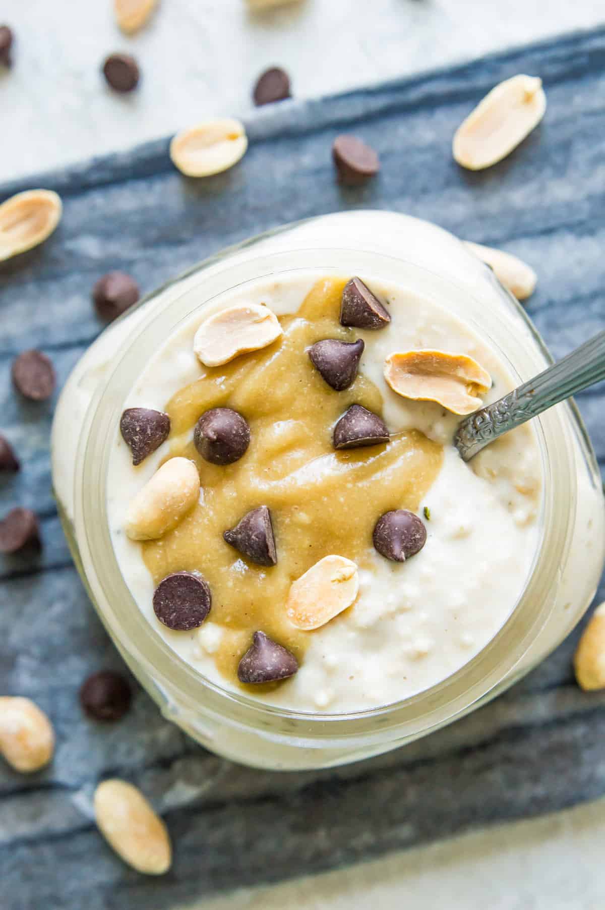A jar of Snickers overnight oats topped with caramel sauce, peanuts and chocolate chips. 