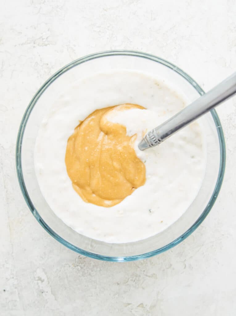 A glass bowl with caramel sauce and milk in it.