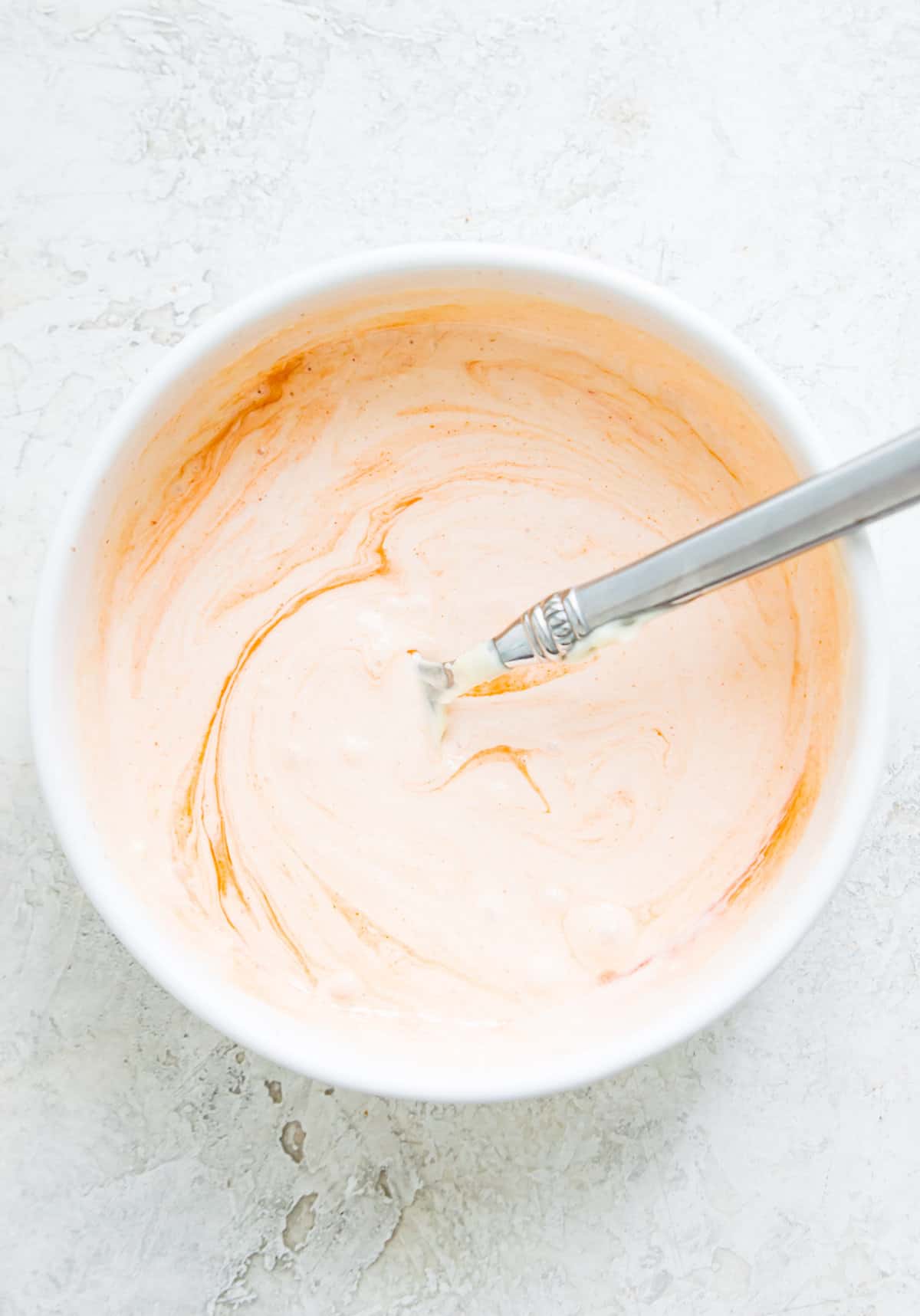 A bowl with aioli in it with a spoon in it.