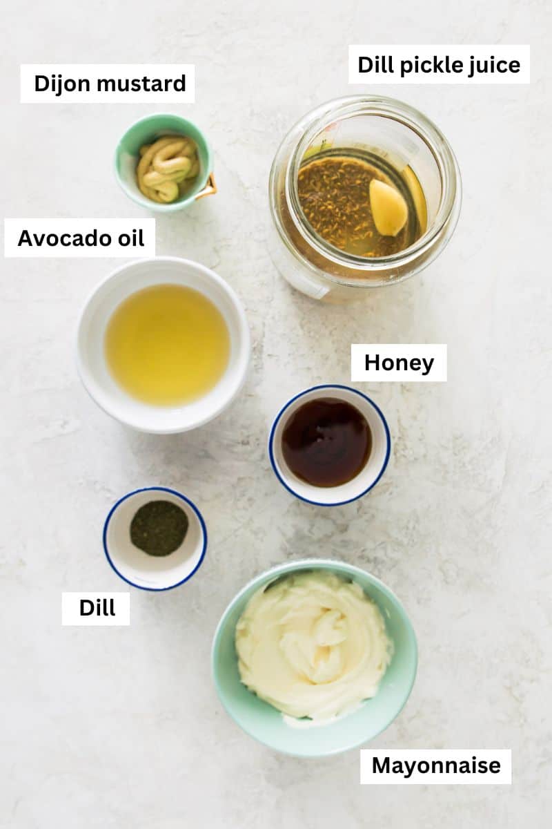 The ingredients needed to make pickle juice salad dressing separated into bowls including avocado oil, dried dill, honey, pickle juice and mayonnaise.