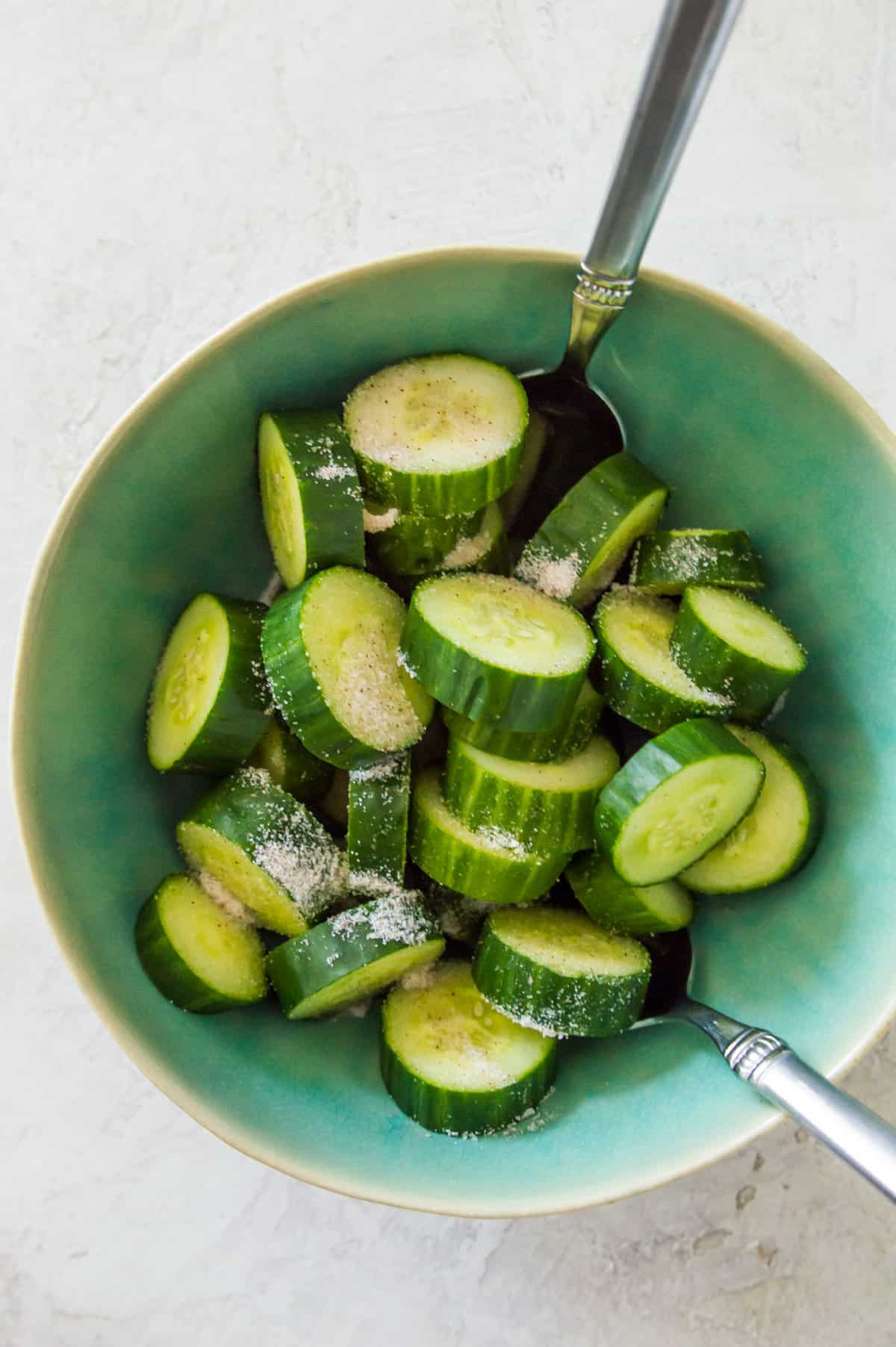 Chopped cucumbers in a bowl topped with salt.