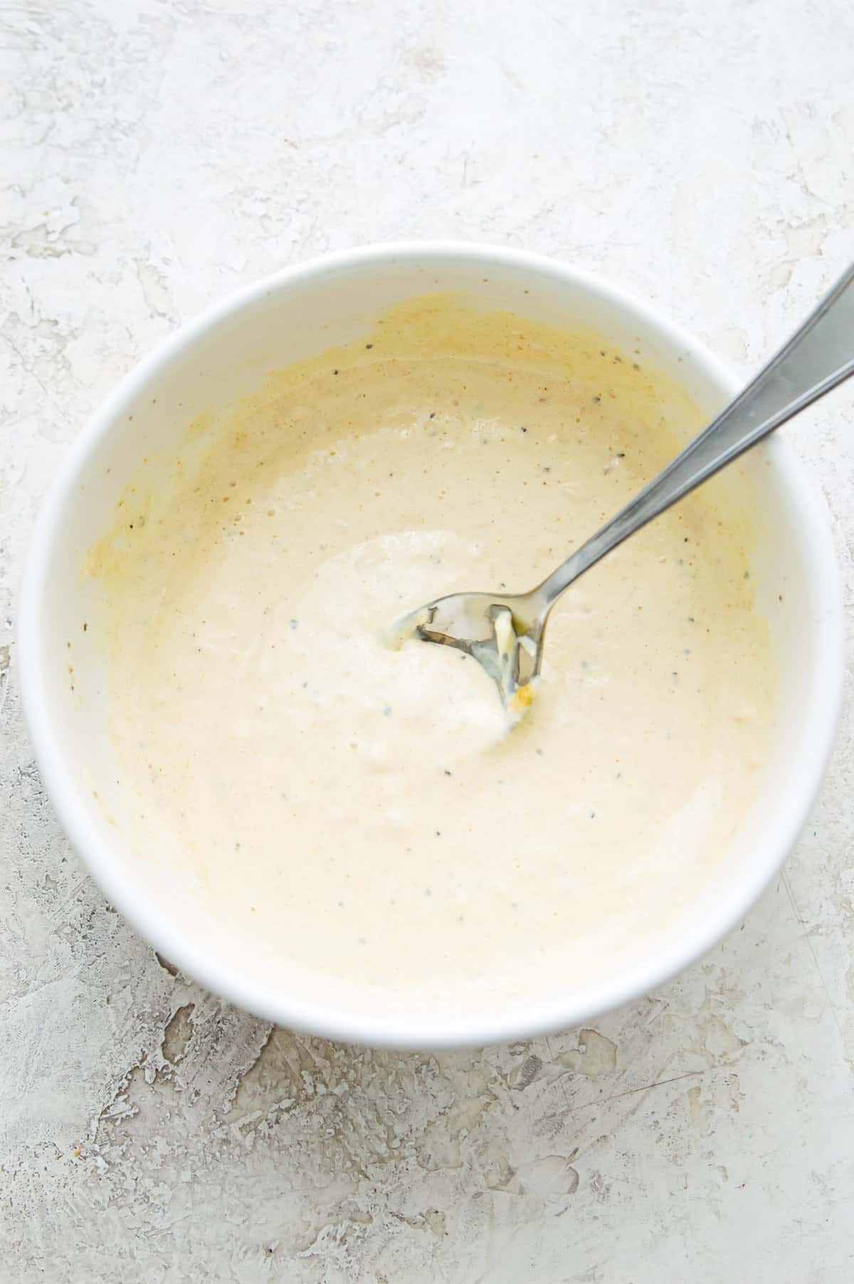 A bowl with aioli in it with a spoon in it.