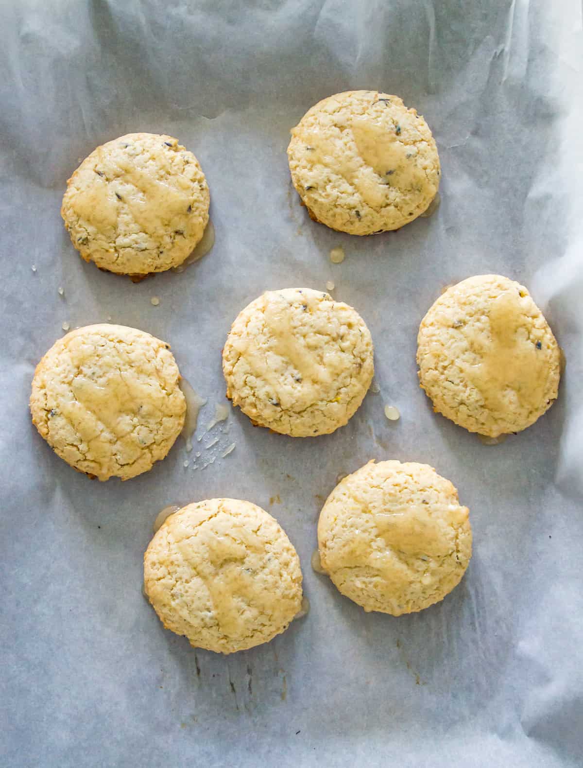 Baked cookies with a glaze on them on a piece of parchment paper.
