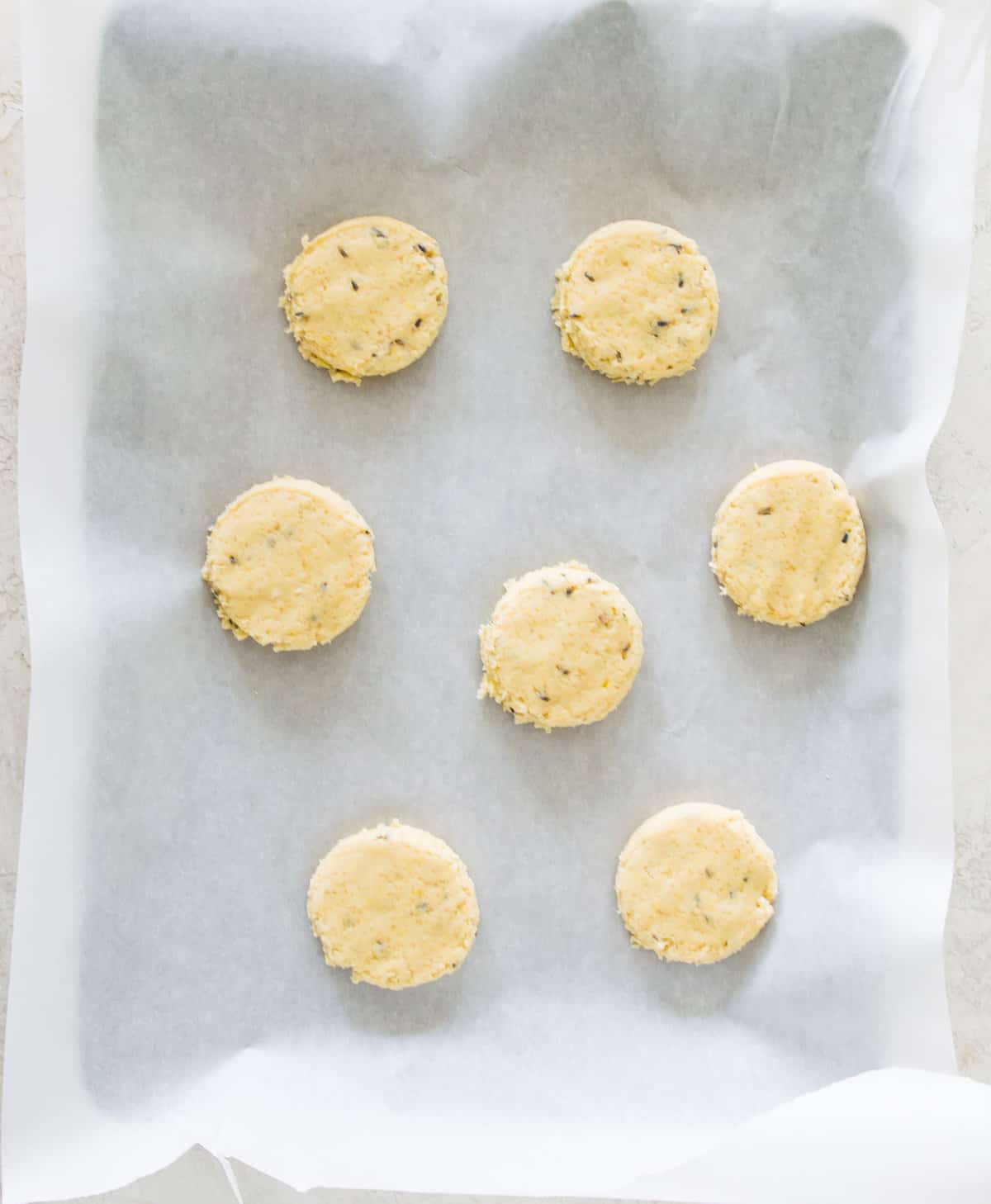 Rounds of raw cookie dough on a baking sheet lined with parchment paper. 