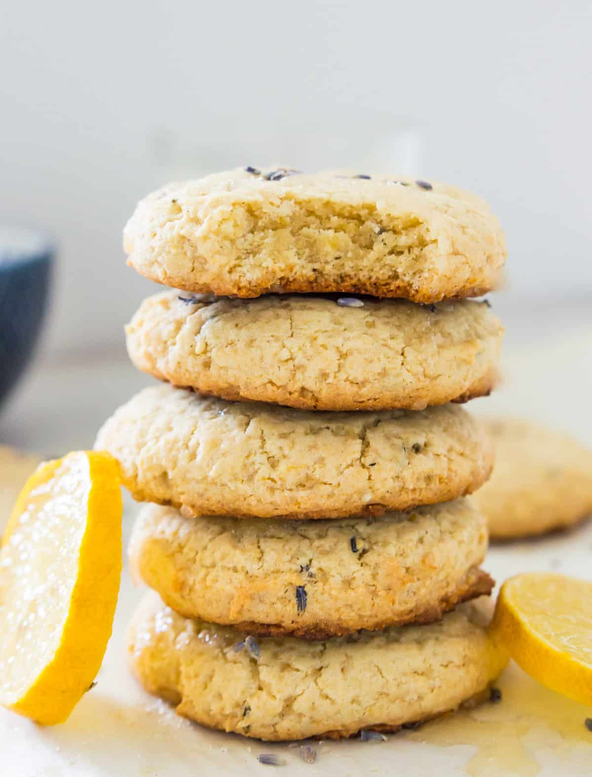 A stack of five lemon and lavender cookies and the top cookie has a bite out of it.