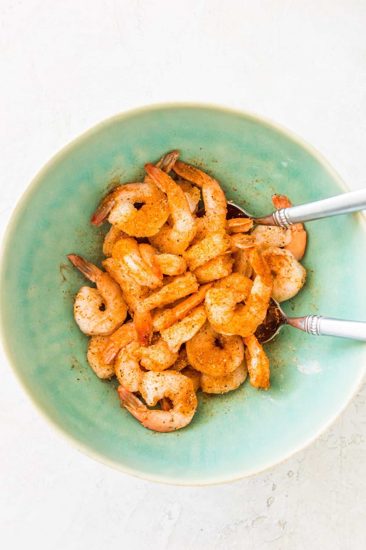 Shrimp in a bowl being tossed in a seasoning mix.