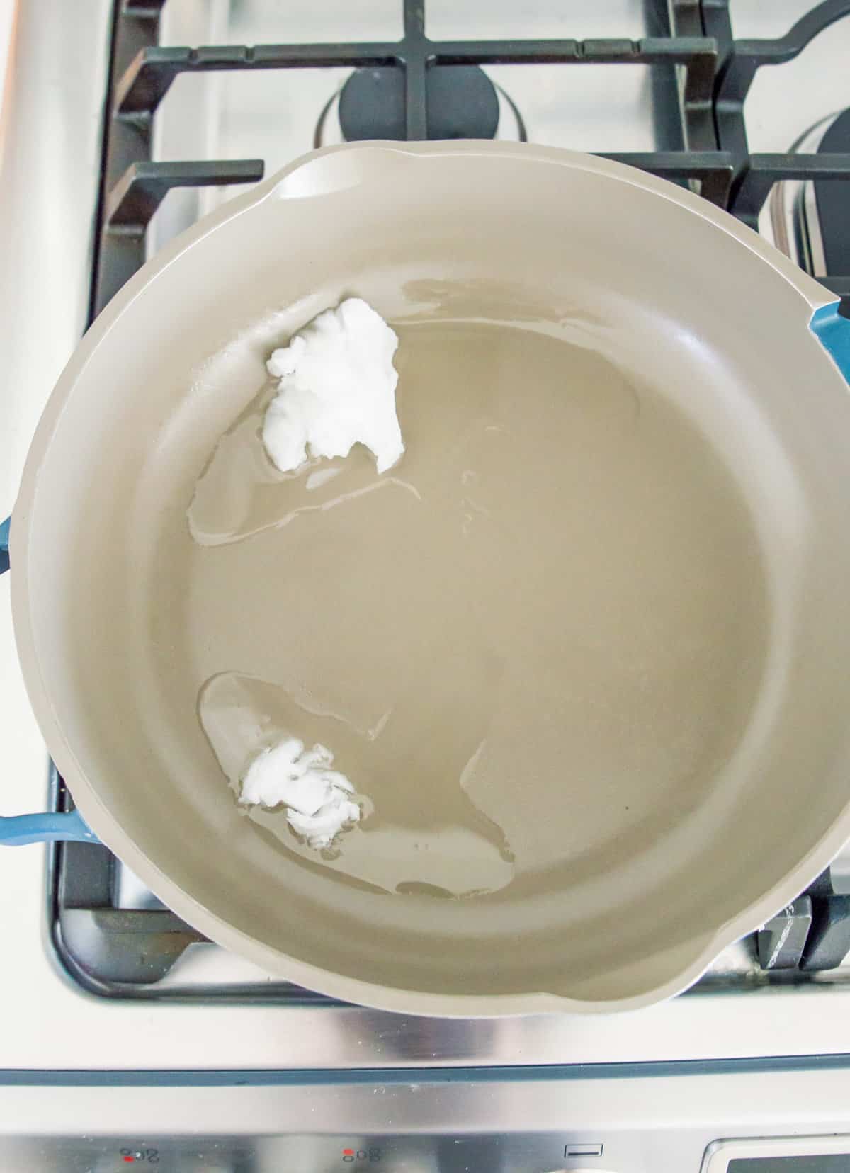 Coconut oil melting in a pan on the stovetop.