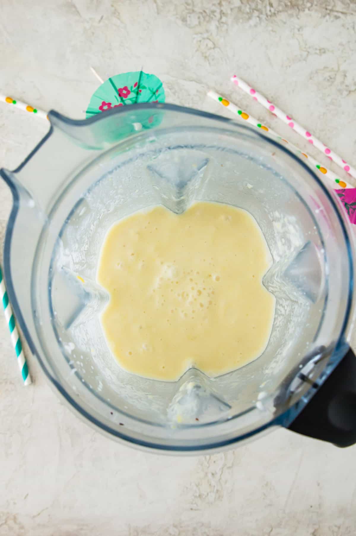 A blender filled with a blended yellow drink. 