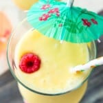 A virgin Pina colada topped with a fresh raspberry and a drink umbrella.