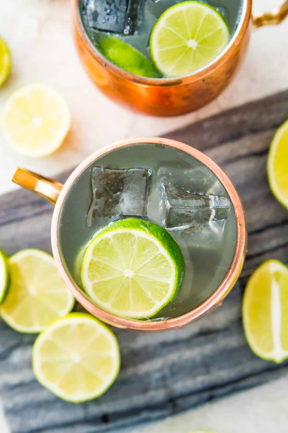A copper mug filled with liquid and ice cubes and topped with a lime slice.