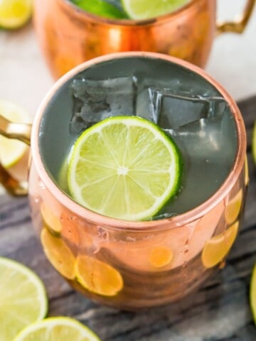 A copper mug filled with a virgin Moscow mule and topped with a lime wedge and ice cubes.