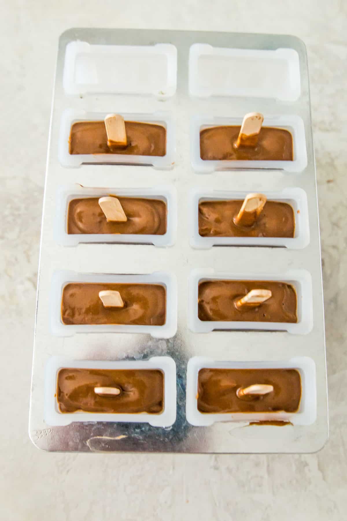 A popsicle mold filled with chocolate popsicles.