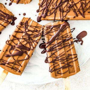 Chocolate fudgesicles drizzled in melted chocolate on a serving tray.