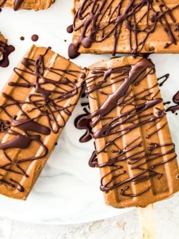 Chocolate fudgesicles drizzled in melted chocolate on a serving tray.