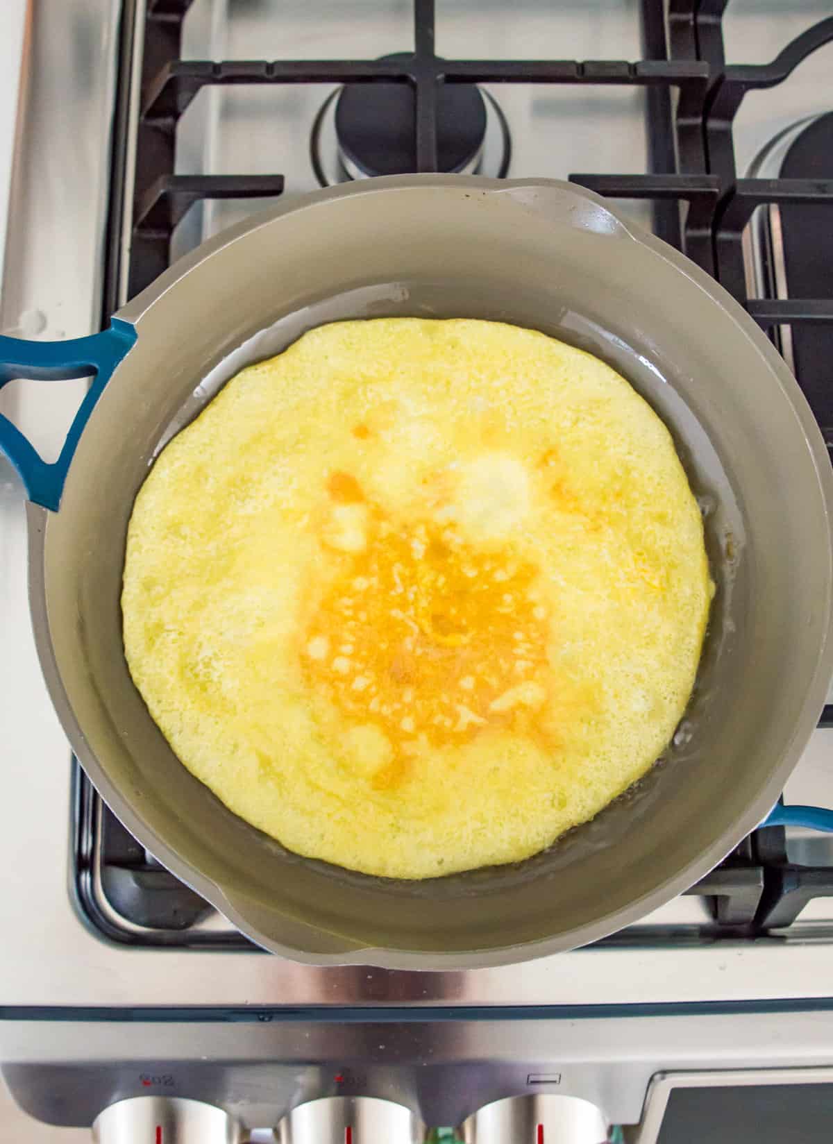 Eggs frying in a pan on a stovetop.