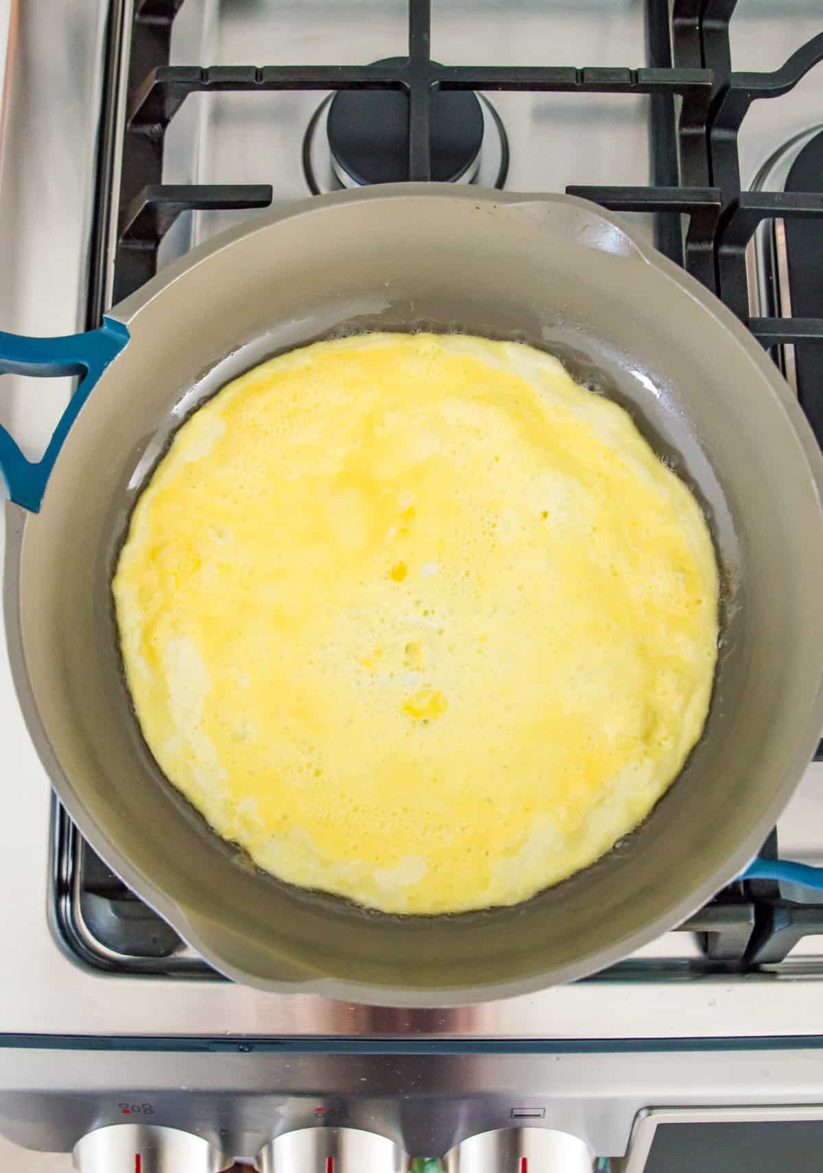 Eggs frying in a pan on a stovetop.