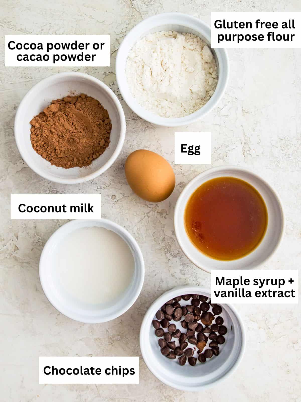 The ingredients needed to make a gluten free chocolate mug cake separated into small bowls. 