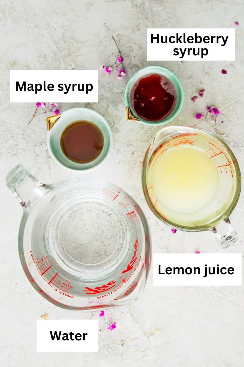 The ingredients needed to make huckleberry lemonade including maple syrup, water, lemon juice and huckleberry syrup separated into bowls.