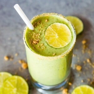 A glass of a key lime pie smoothie topped with a lime slice and crushed graham crackers.