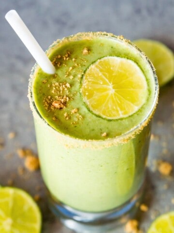 A glass of a key lime pie smoothie topped with a lime slice and crushed graham crackers.