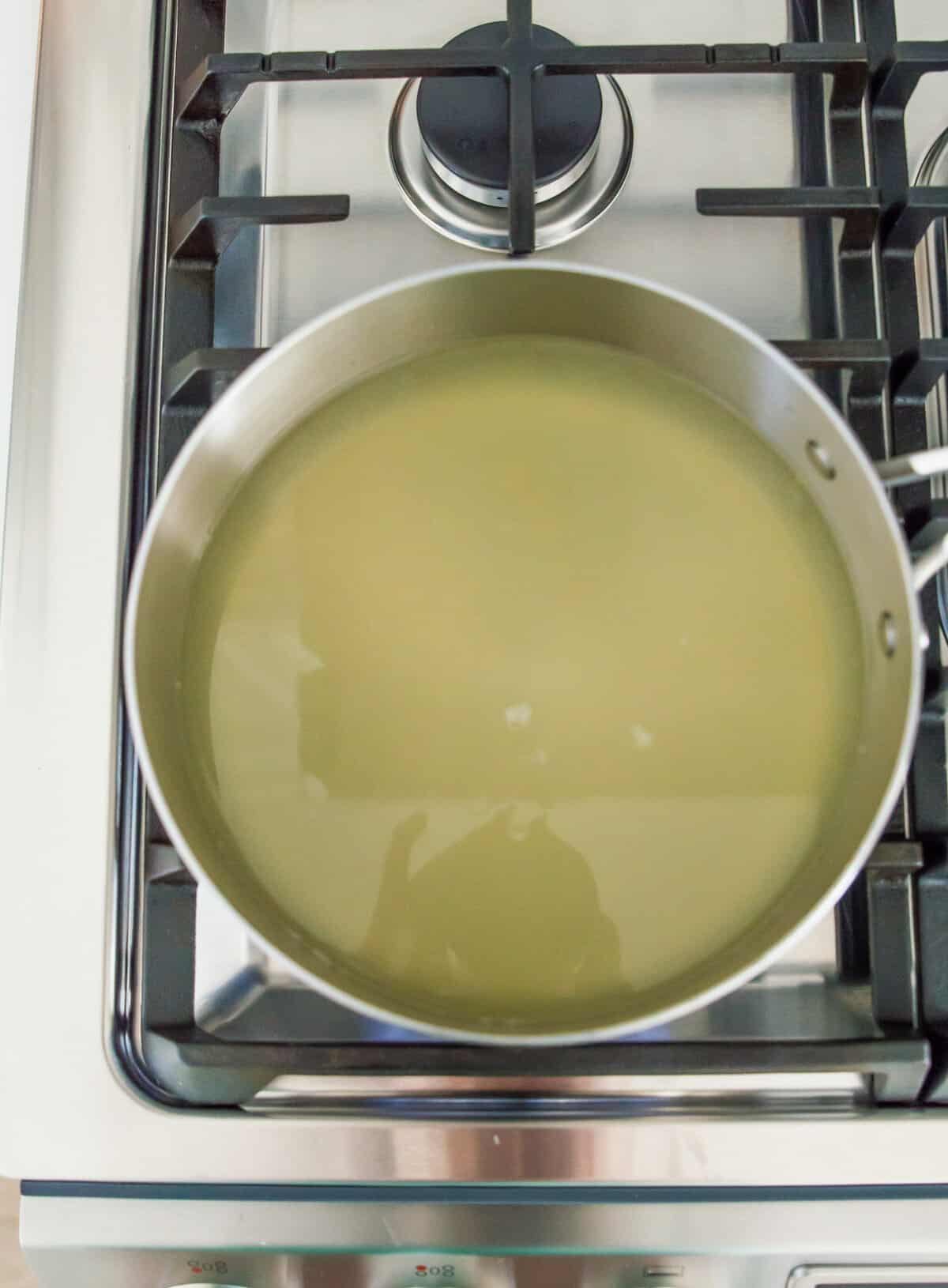 A stainless steel pot on the stovetop with lemon water in it.