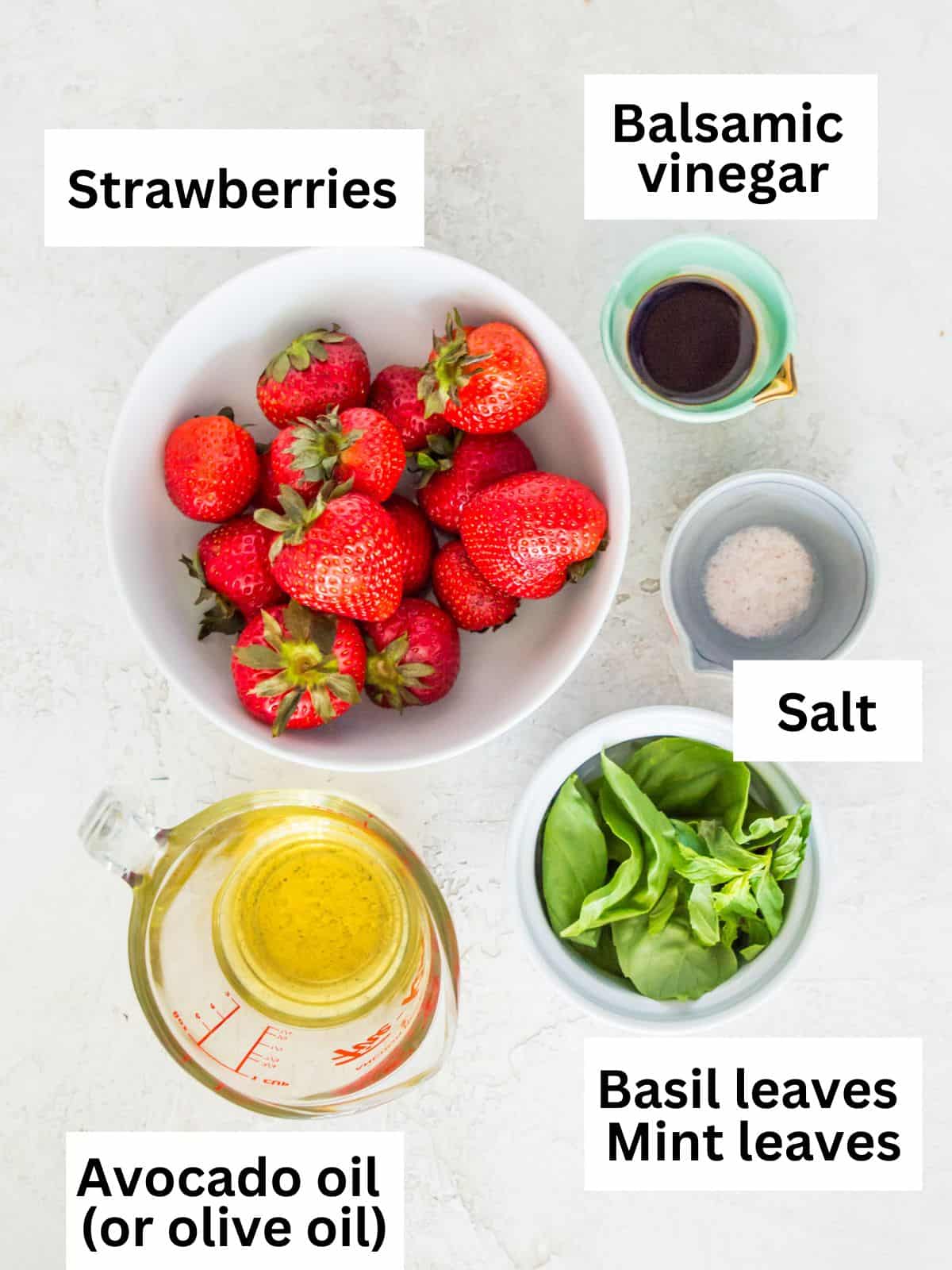 The ingredients needed to make a strawberry basil vinaigrette separated into small bowls. 