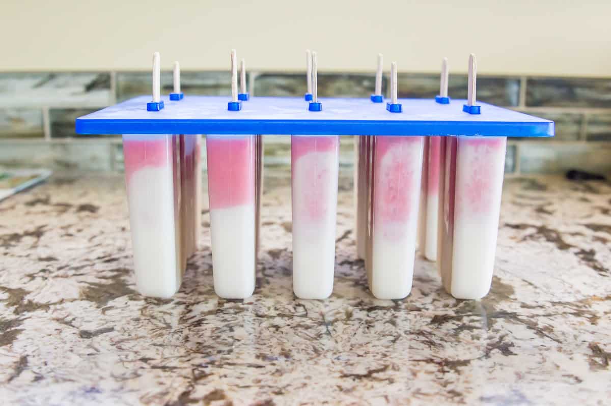 A popsicle mold filled with strawberry vanilla popsicles.