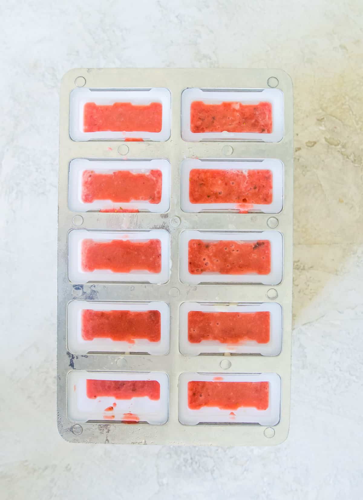 A popsicle mold filled with blended strawberries.
