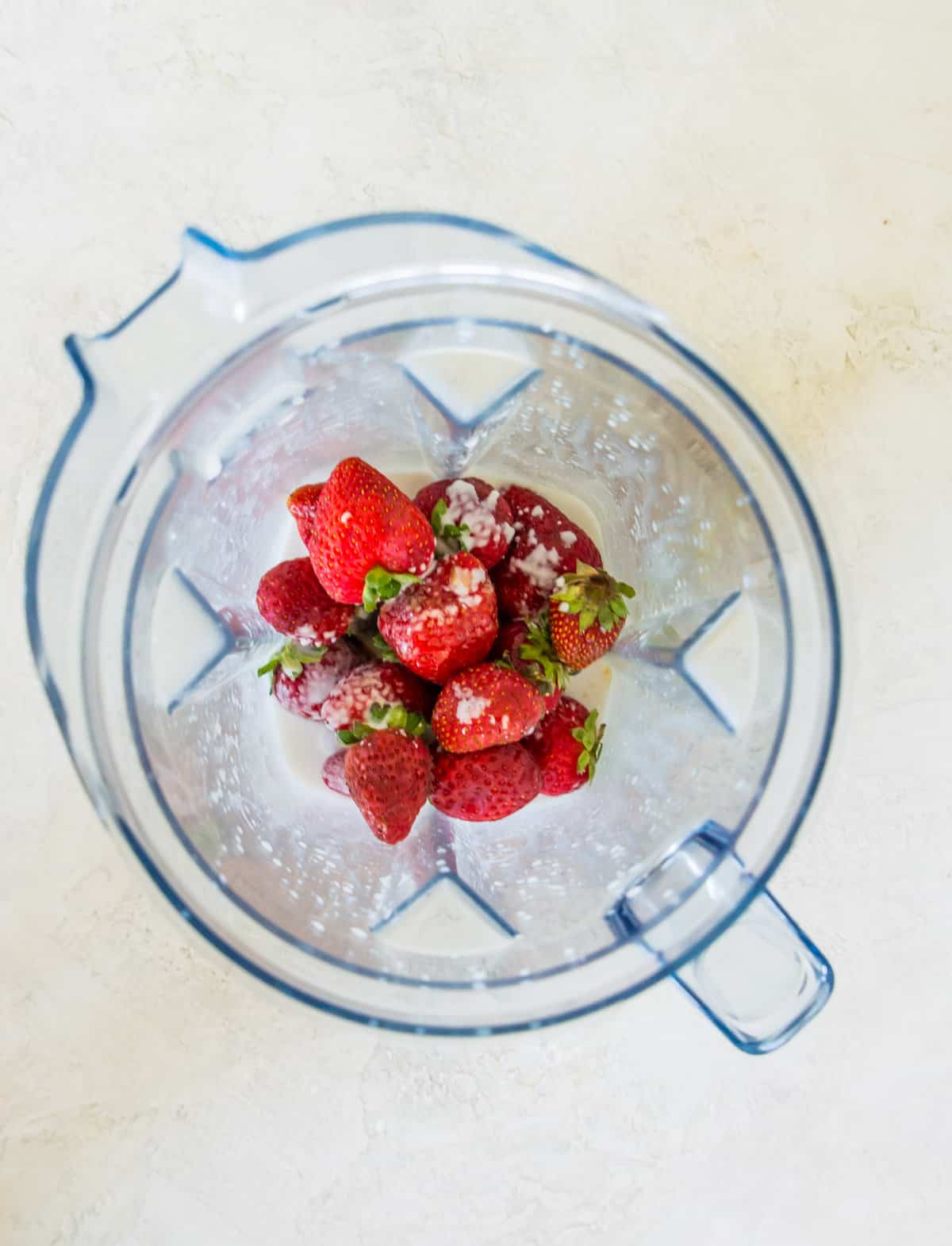 Strawberries and coconut milk in a blender.