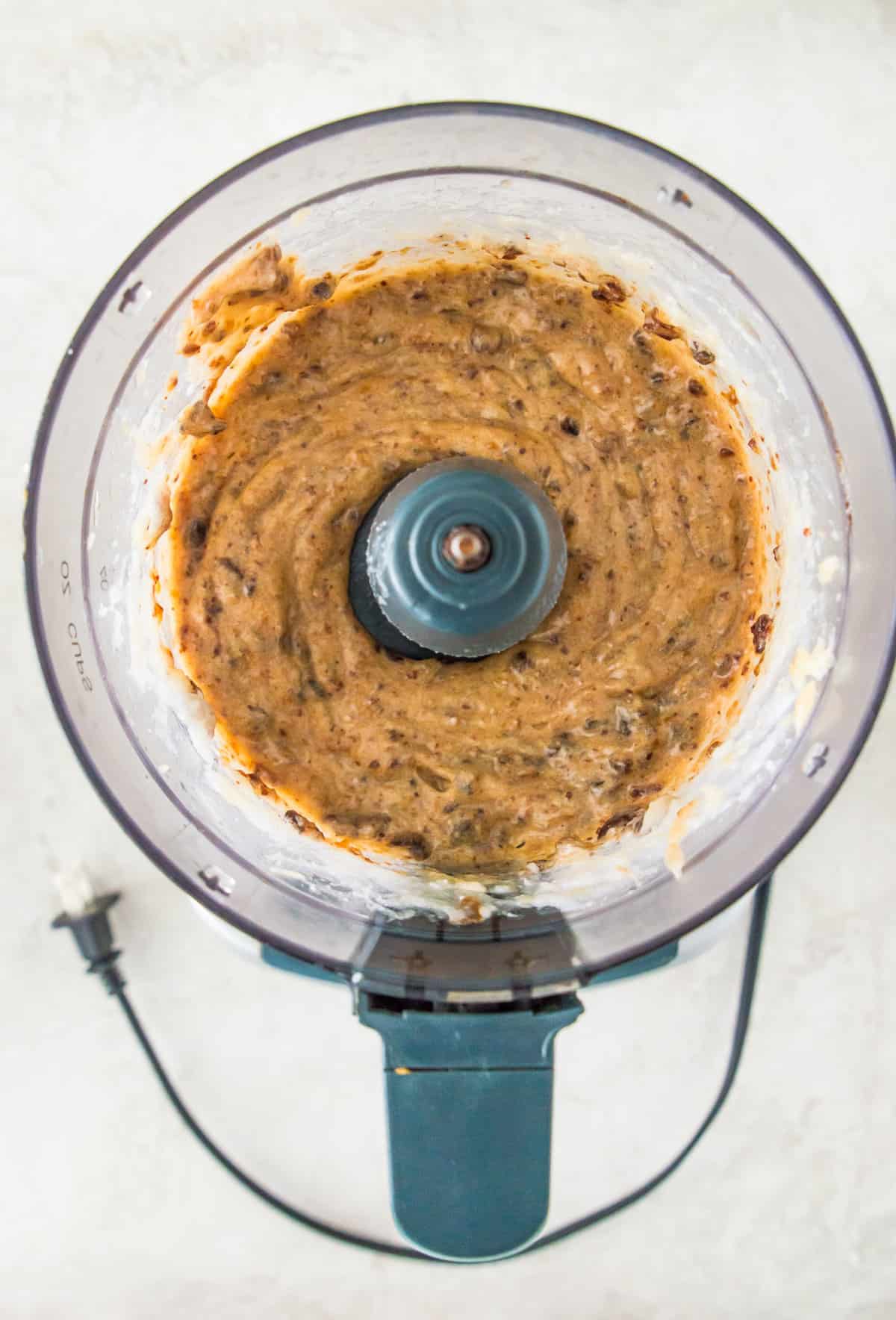 A food processor with blended bananas and dates in it.