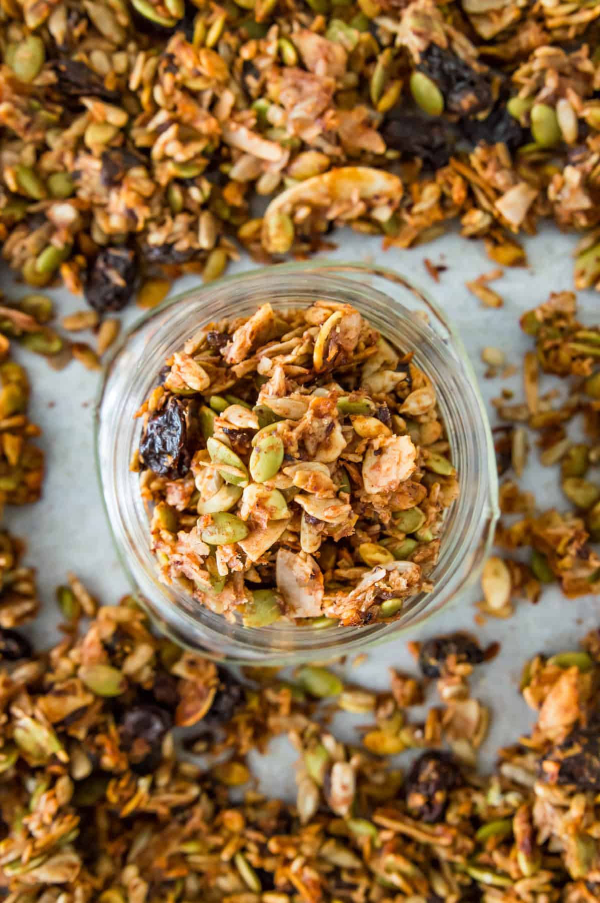 A jar full of grain free granola on a baking sheet covered in granola. 