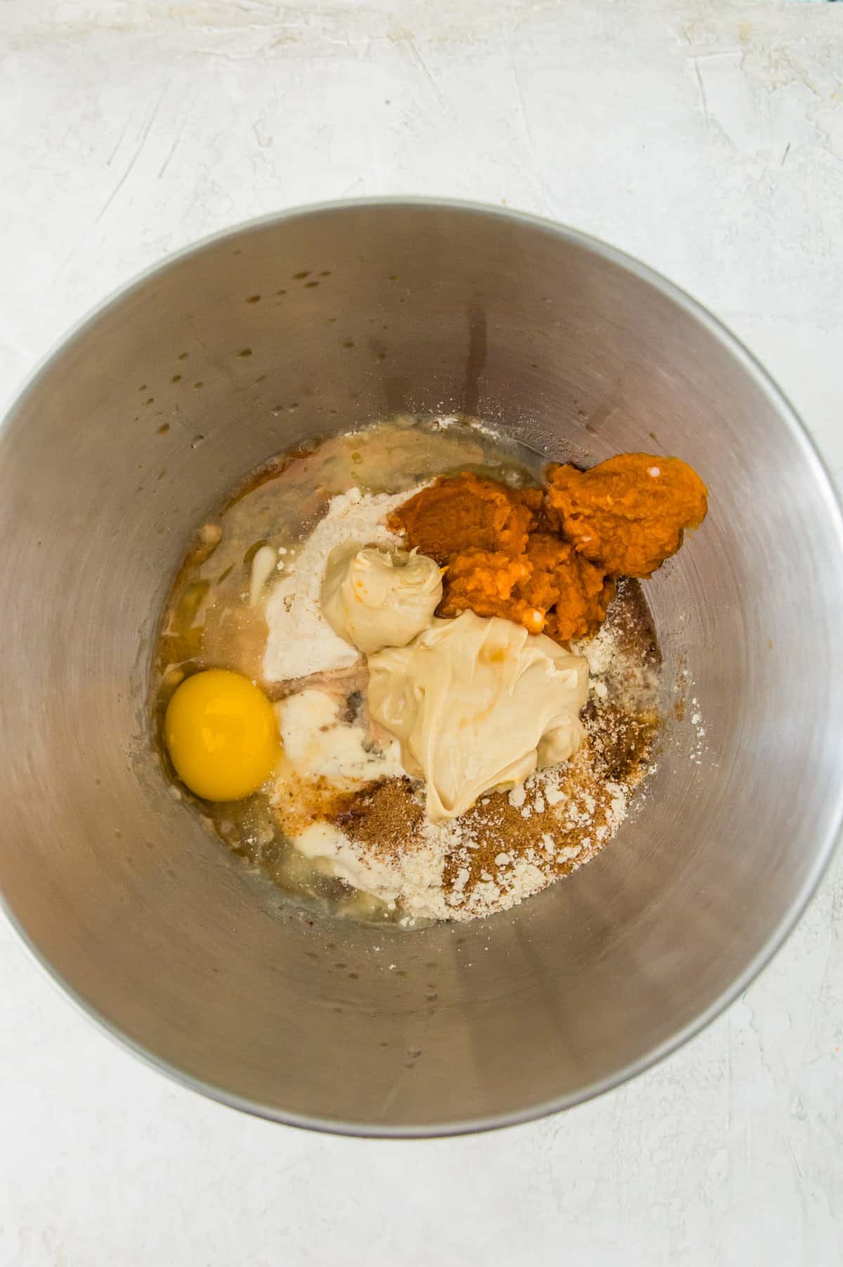 Almond flour, coconut sugar, pumpkin puree, cashew butter, an egg and coconut oil in a bowl.