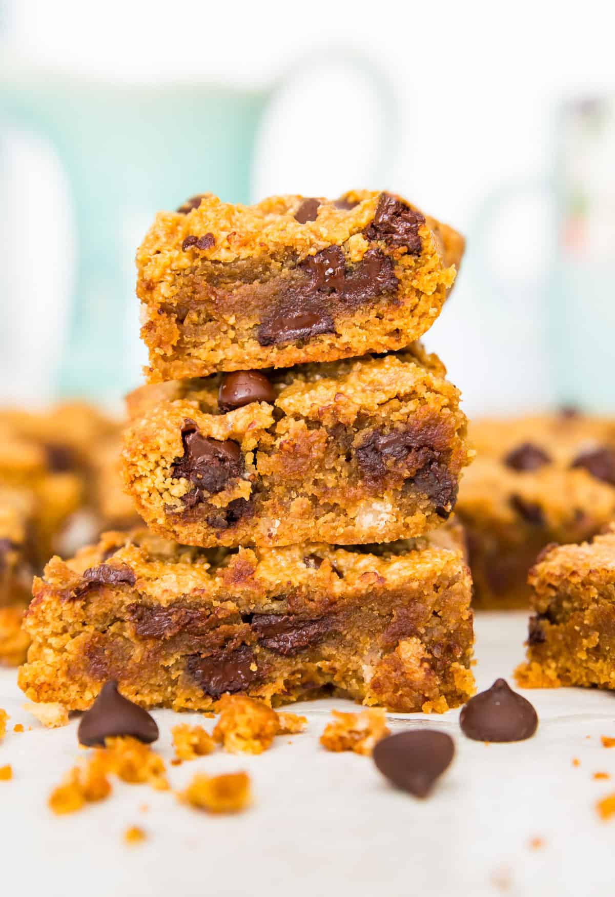 A stack of three pumpkin chocolate chip cookie bars with chocolate chips around them.