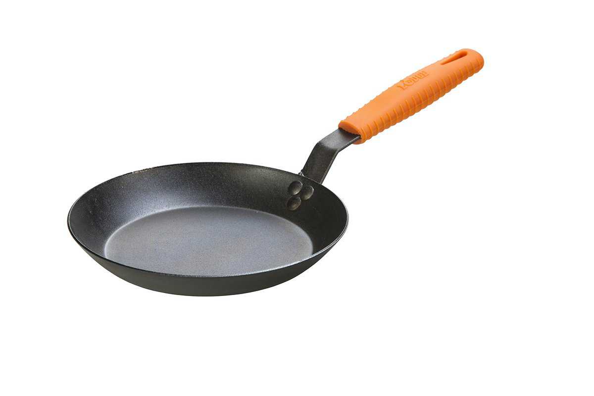 A Lodge carbon steel skillet with an orange silicone handle.