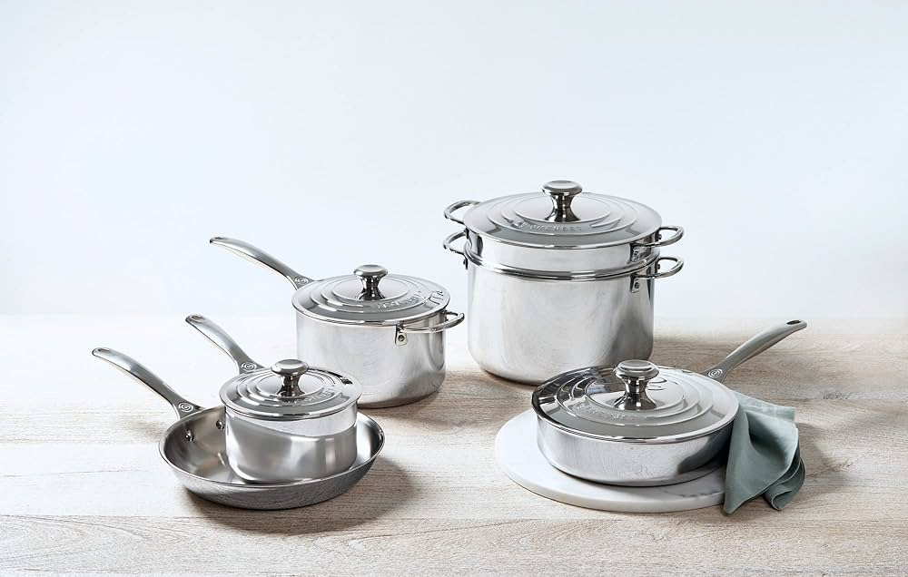 A set of Le Creuset stainless steel cookware including 2 pans and 3 pots. 
