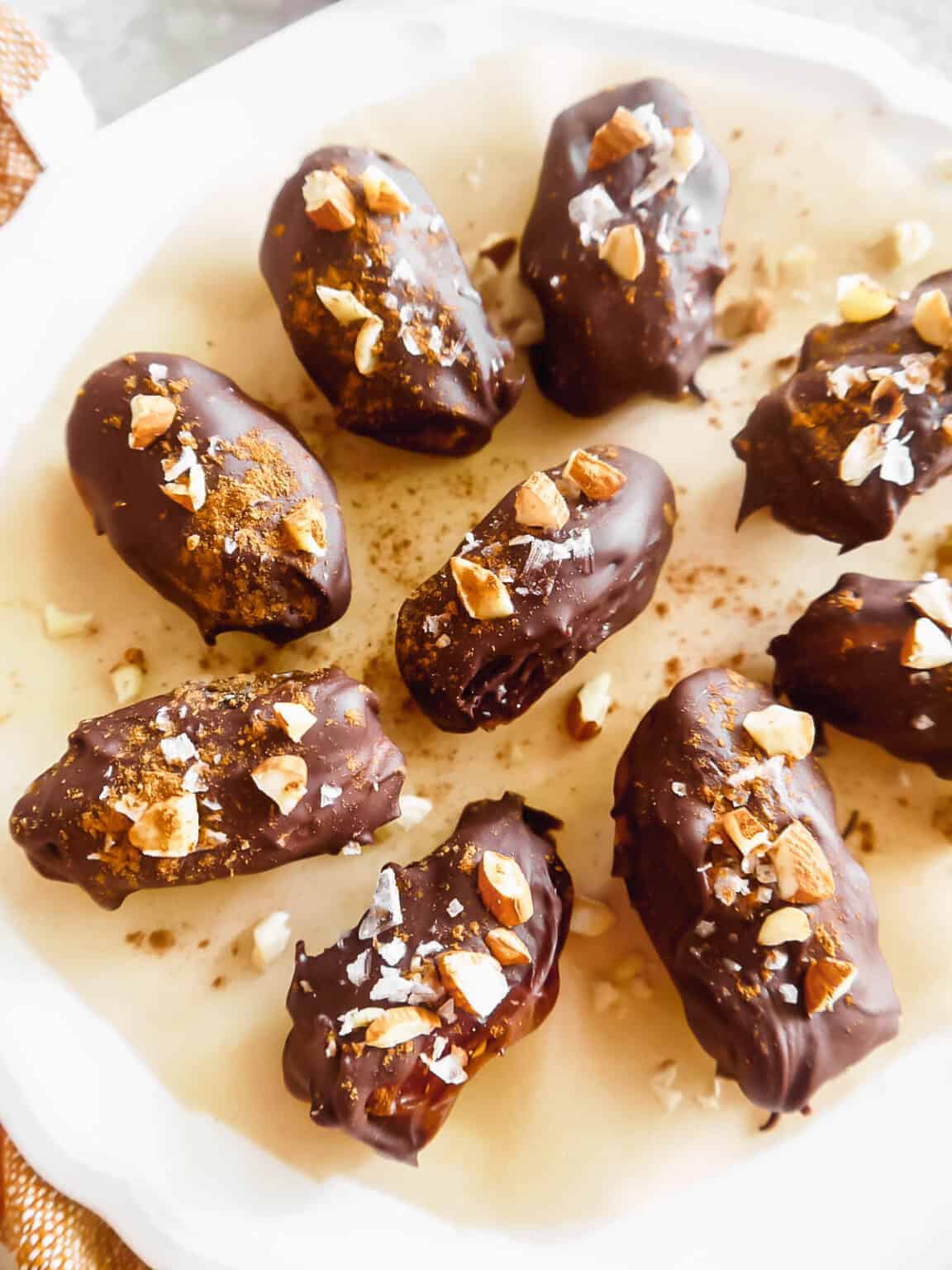 A plate with paleo chocolate-covered dates topped with crushed almonds.