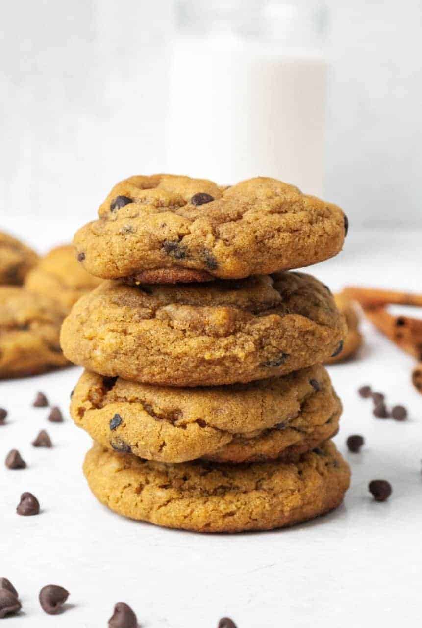 A stack of four paleo gingerbread chocolate chip cookies surrounded by chocolate chips.
