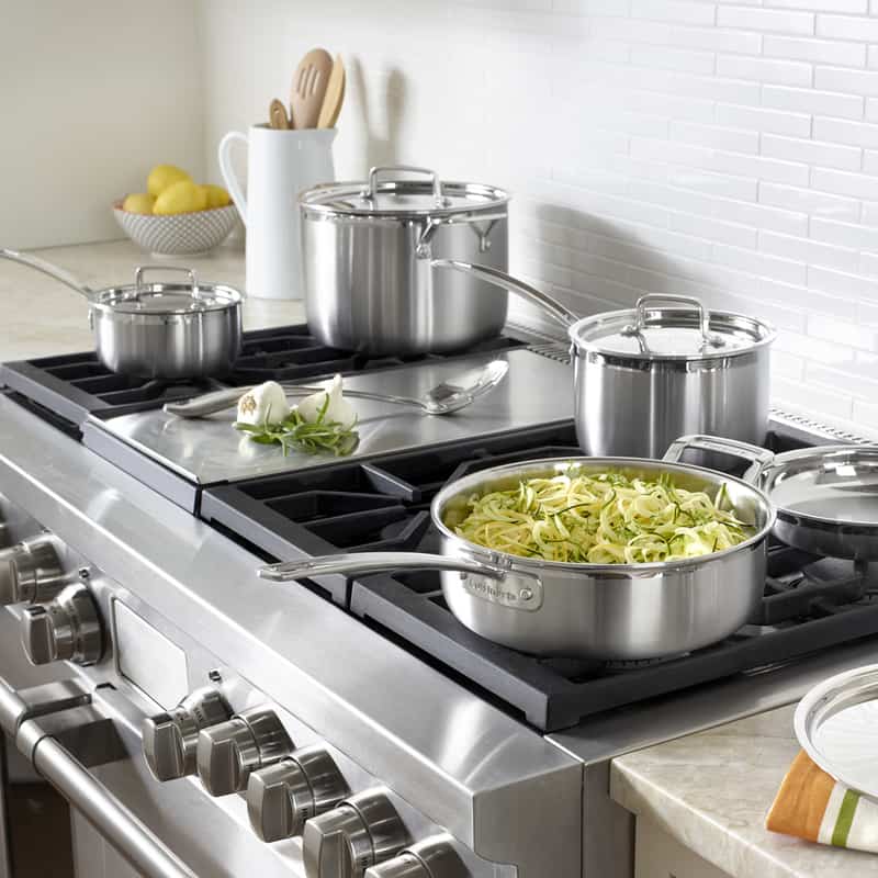 A set of Cuisinart multi clad cookware being used to cook zucchini noodles on a stovetop.