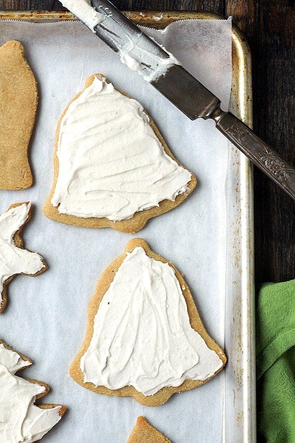 Paleo frosted sugar cookie cut-outs on a baking sheet lined with parchment paper.