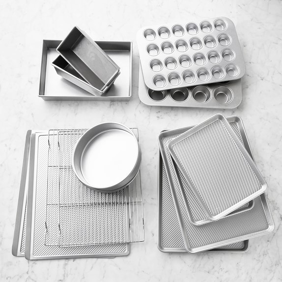 A bunch of different sizes of stainless steel bakeware including muffin pans, round cake pans, square pans, baking sheets and loaf pans. 