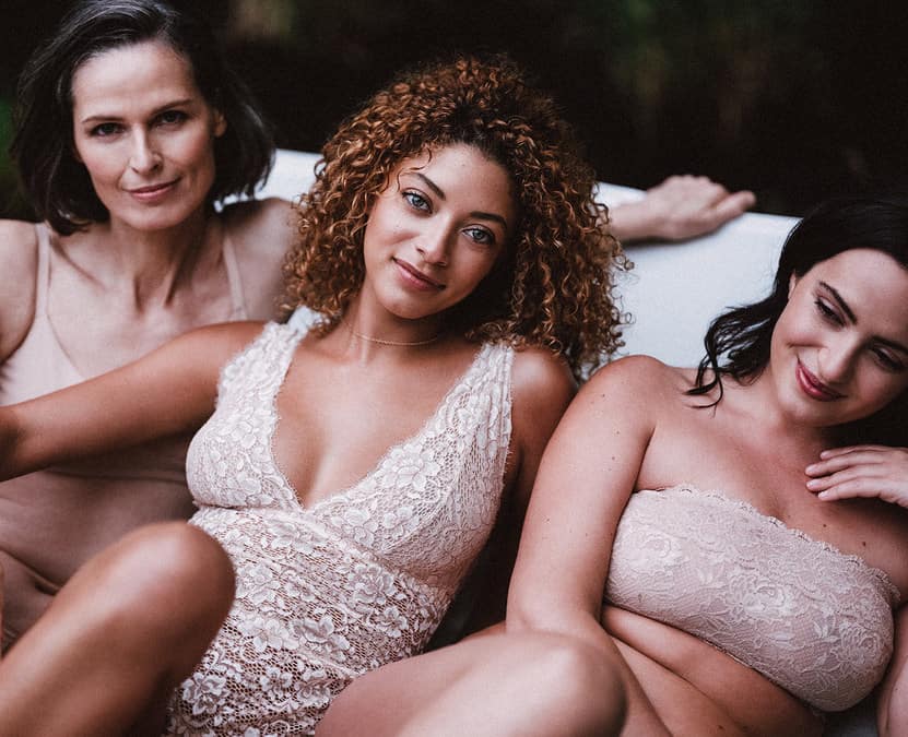 Three women wearing Cosabella lingerie in different styles of lace bras and underwear.