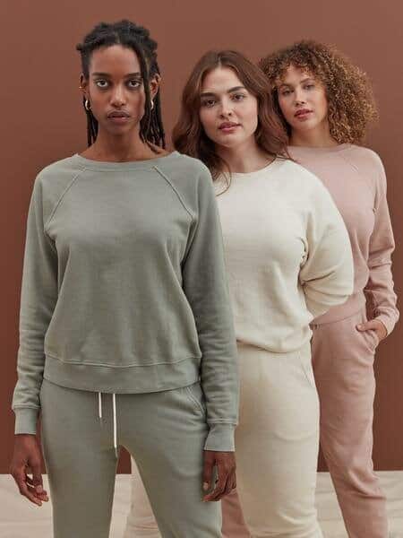 Three girls wearing sweatsuits from the brand MATE the label in different colours including green, white and pink.