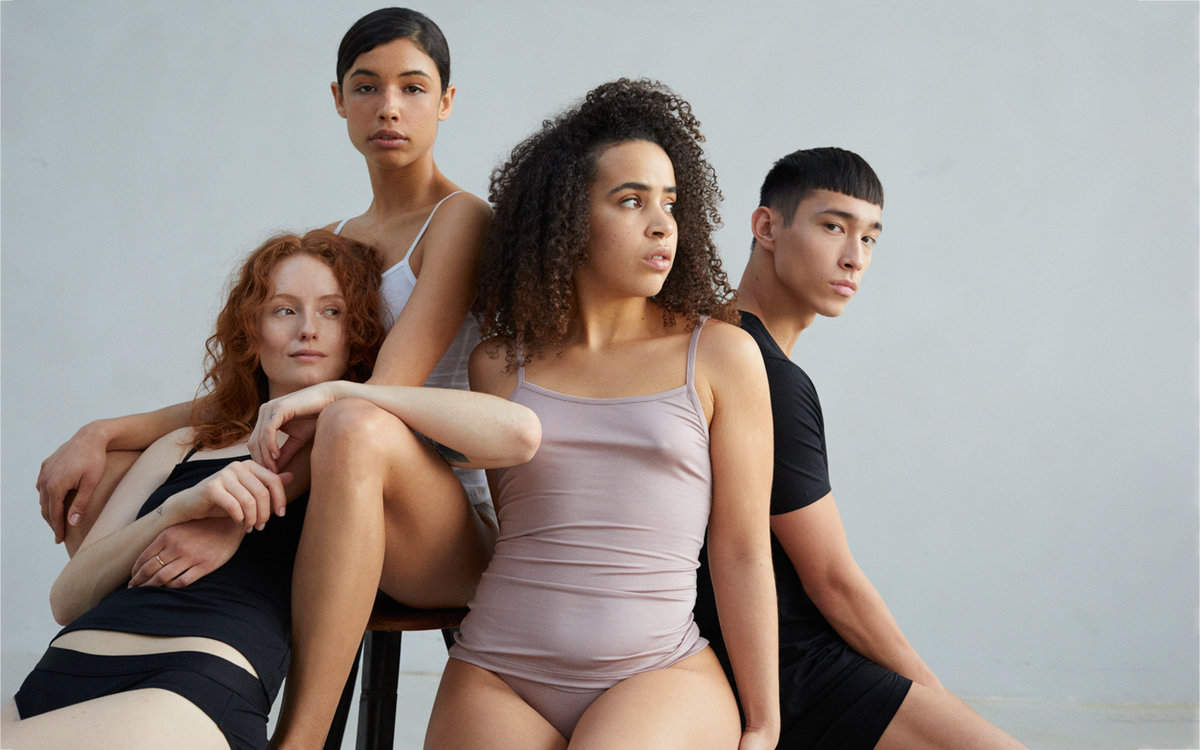 Three women and a man wearing tank tops and boy shorts in different colours including pink, white and black.