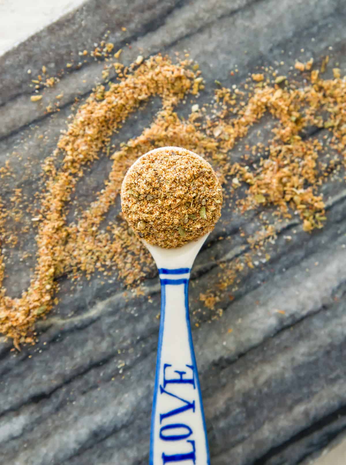 A serving spoon with carne asada seasoning in it and spilling out of it.