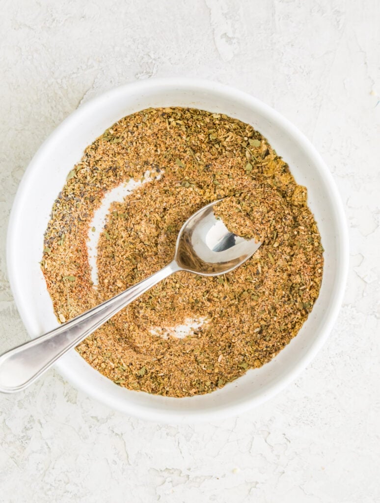 A bowl with a seasoning blend in it and a spoon in it.