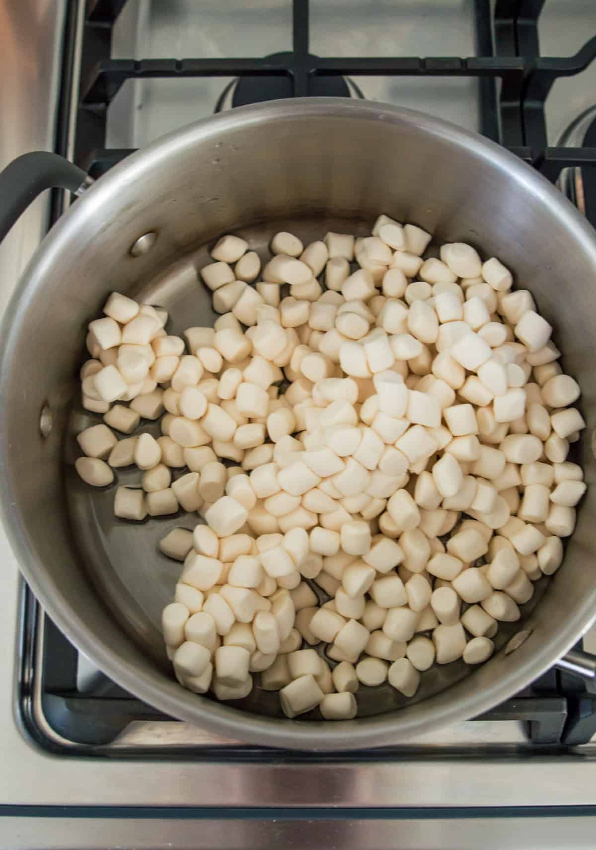 A large pot on the stovetop with mini marshmallows in it.