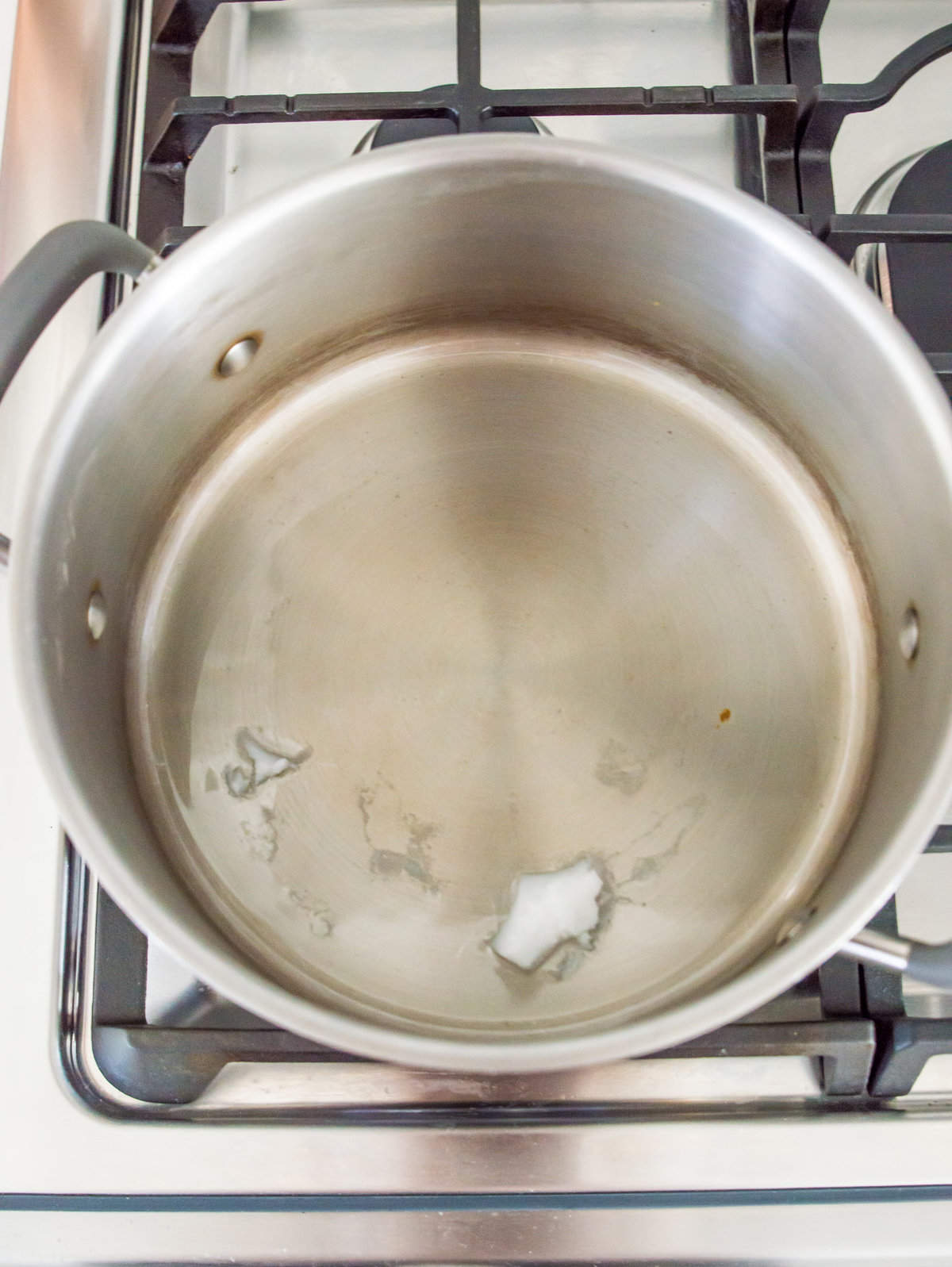 A pot on the stovetop with coconut oil melting in it.