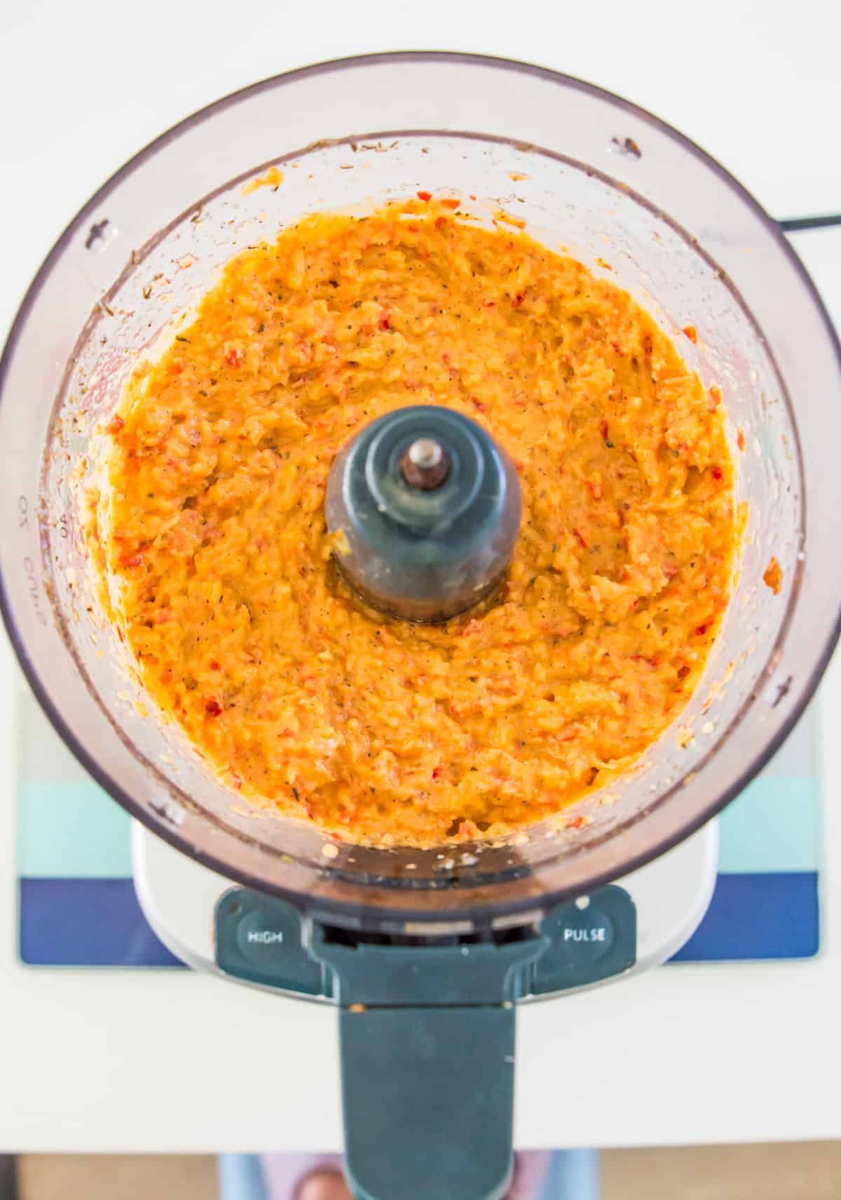 A food processor with a roasted red pepper dip that has been blended in it.