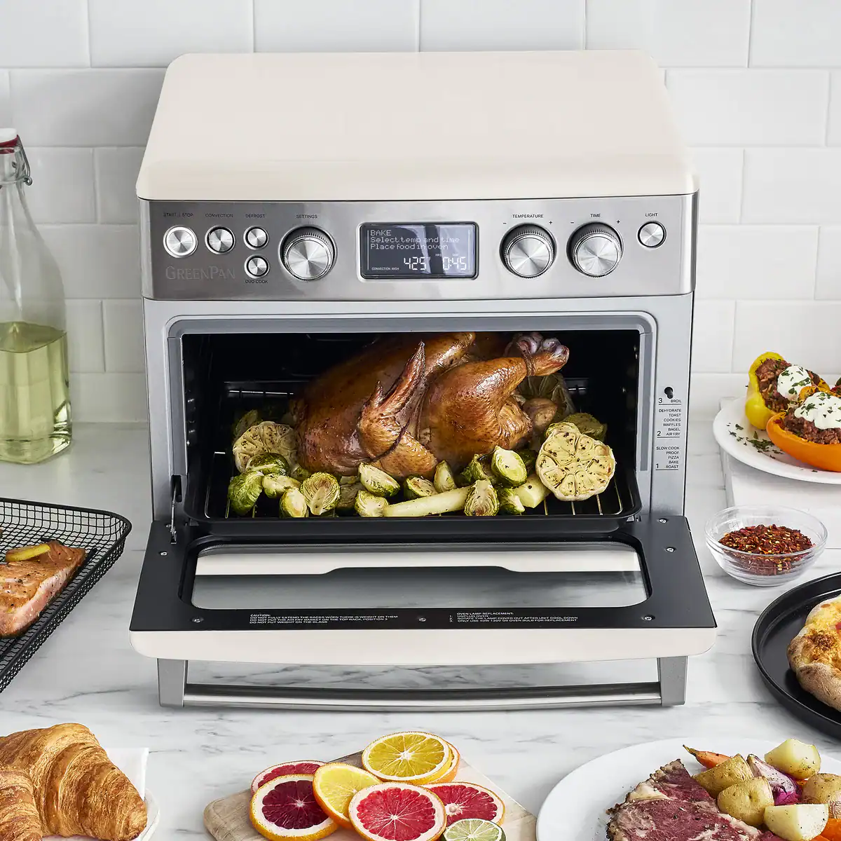 A white toaster oven on a countertop with a roasted chicken in it.