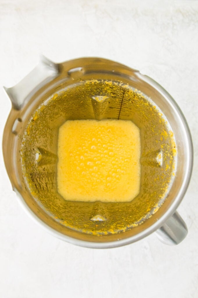 A metal blender filled with orange juice.